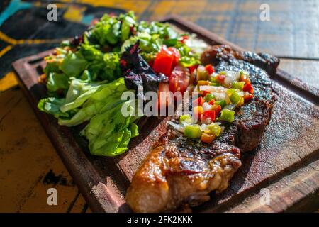 Chorizo/Churrasco-Steak mit kreolischer Sauce und Salat (typisch argentinische Küche). Stockfoto
