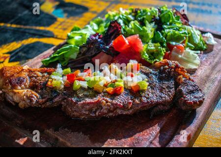 Chorizo/Churrasco-Steak mit kreolischer Sauce und Salat (typisch argentinische Küche). Stockfoto