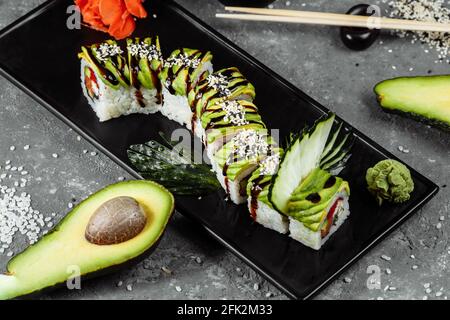 Sushi-Rolle mit grünem Drachen, Aal, Avocado, Gurke und Ingwer, begleitet von gebratenen Tempura-Garnelen. Traditionelle asiatische Reis Sushi gesunde Meeresfrüchte Stockfoto