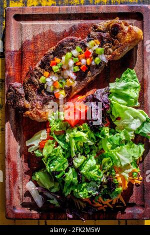 Chorizo/Churrasco-Steak mit kreolischer Sauce und Salat (typisch argentinische Küche). Stockfoto