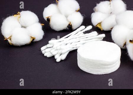 Weiße weiche Wattepads und -Sticks für Hygiene und Gesundheit auf schwarzem Hintergrund. Stockfoto