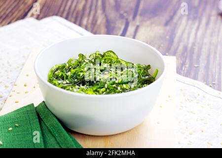 Grüner asiatischer Algensalat in einer weißen Schüssel auf Holzgrund. Stockfoto