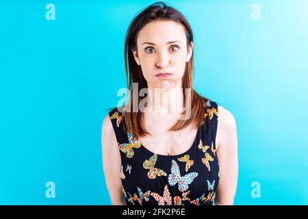 Schöne Erwachsene junge Frau mit gelber Jacke und blauem Hintergrund mit geschwollenen Wangen. Stockfoto