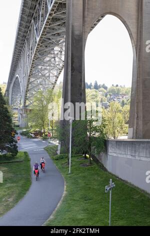 Ein Paar fährt auf dem Burke-Gilman Trail im Stadtteil Fremont in Seattle mit Elektrofahrrädern entlang der Aurora Bridge. Stockfoto