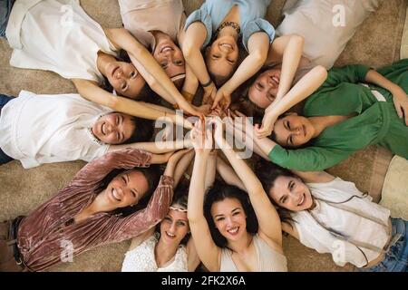 Glückliche Freundinnen liegen Kreis heben die Hände zusammen genießen Freundschaft Zusammenarbeit Stockfoto