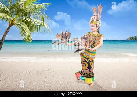 Asiatische Frau, die traditionellen Tanz in Ost-Kalimantan tanzt (Giring-Giring-Tanz) Am Strand Stockfoto