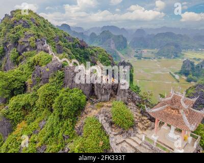 Familie von Touristen auf dem Hintergrund der erstaunlichen riesigen Drachenstatue auf Kalkstein Berggipfel in der Nähe Hang Mua Aussichtspunkt am nebligen Morgen. Beliebt Stockfoto