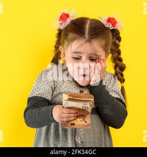 Glückliches Kind, das Geld hält, Kinderfreude in viel Geld, Porträt eines Mädchens auf gelbem Hintergrund. Stockfoto