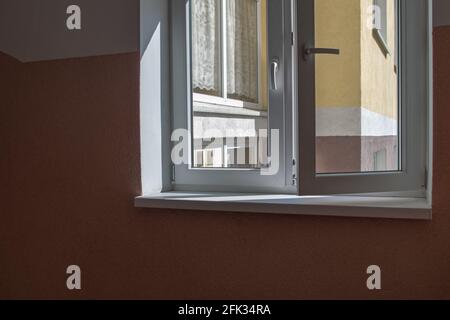 Blick von innen auf den Eingang mit eingemalter Wand Beige Farbe an der Ecke und Fenster des Wohnens Gebäude durch ein weißes Kunststofffenster Stockfoto
