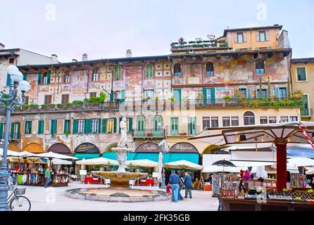 VERONA, ITALIEN - 23. APRIL 2012: Antike römische Skulptur von Madonna Verona Brunnen vor den Marktständen, Restaurant und Case Mazzanti Haus Stockfoto