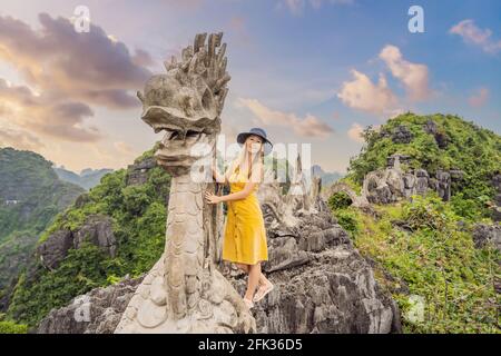 Frau Tourist auf dem Hintergrund der erstaunlichen riesigen Drachenstatue auf Kalkstein Berggipfel in der Nähe Hang Mua Aussichtspunkt am nebligen Morgen. Beliebter Tourist Stockfoto