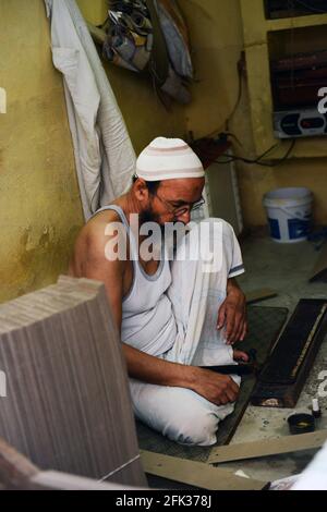 Ein muslimischer Handwerker, der an einem Druckblock für indischen Saree arbeitet. Stockfoto