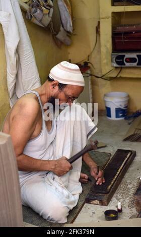 Ein muslimischer Handwerker, der an einem Druckblock für indischen Saree arbeitet. Stockfoto