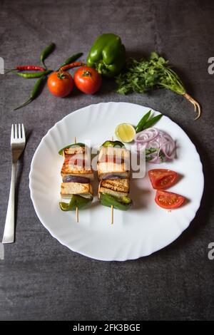 Draufsicht auf Paneer Tikka in einem Teller. Paneer oder Quark Tikka ist ein indisches Gericht aus Brocken Paneer mariniert mit Gewürzen zusammen mit Gemüse Stockfoto