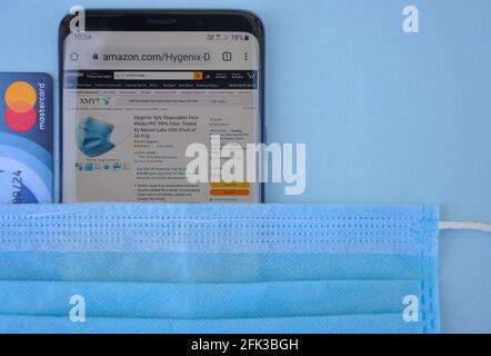 Mandi, Himachal Pradesh, Indien - 03 04 2021: Hoher Winkel des Kaufens der medizinischen Maske online mit Mastercard, Amazon-Website auf Smartphone, das ein weltweit Top-internationales elektronisches Handelsunternehmen ist Stockfoto