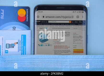 Mandi, Himachal Pradesh, Indien - 03 04 2021: Hoher Winkel des Kaufens der medizinischen Maske online mit Mastercard, Amazon-Website auf Smartphone, das ein weltweit Top-internationales elektronisches Handelsunternehmen ist Stockfoto
