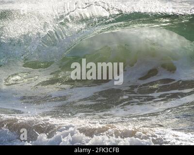 Klares Wasser Surfen, Nahaufnahme Ozeanwellen, glasartige gewellte Kante einer Röhrenwelle, wenn sie am Strand umrollt Stockfoto