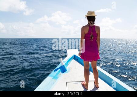 Frau, die auf dem Deck eines Holzboots auf den Malediven steht. Die Malediven sind ein beliebtes tropisches Urlaubsziel im Indischen Ozean. Stockfoto