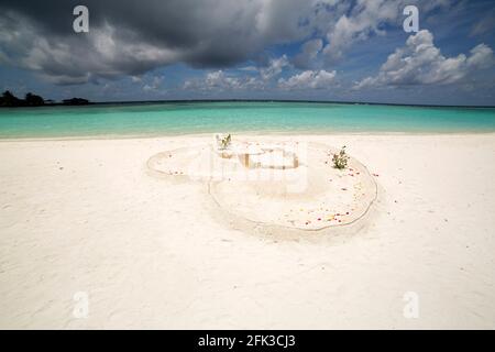 Herz in weißem Sand auf Paradise Island auf den Malediven. Monsunwolken sammeln sich über der tropischen Insel. Stockfoto