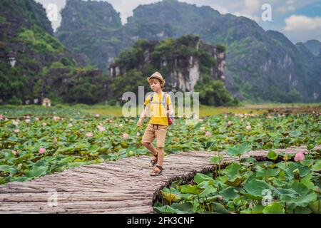 Junge in gelb auf dem Weg zwischen dem Lotussee. Mua Cave, Ninh Binh, Vietnam. Vietnam wird nach dem Coronovirus COVID 19-Quarantänekonzept wieder eröffnet Stockfoto