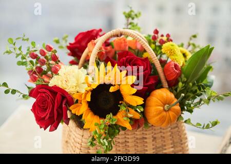 Gemischte Herbstblumen, Sonnenblume, Kürbis, Rose, Physalis im Korb, Bouquet ist auf der Fensterbank. Hochwertige Fotos Stockfoto