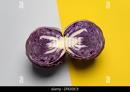 Ein Rotkohl in zwei Hälften geschnitten und auf ein gelegt Farbige Oberfläche Stockfoto