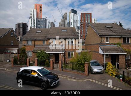 Eine Person fährt eine Wohnstraße in Lambeth mit der Skyline der VNEB (Vauxhall, Nine Elms und Battersea)-Entwicklung im Süden Londons entlang. Bilddatum: Dienstag, 27. April 2021. Stockfoto