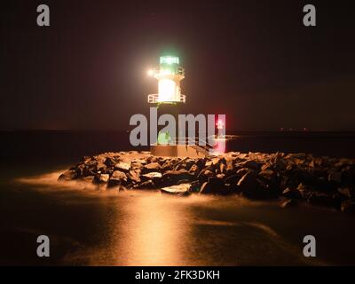 Westmole Leuchtturm, leuchtendes Wellenbrecherlicht an der Mündung eines Hafens. Novembernacht, Warnemünde Strand, Deutschland Stockfoto