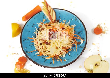 Draufsicht auf geriebenen Apfel mit Karotten in moderner schöner blauer Platte auf weißem Hintergrund. Konzept der richtigen Ernährung ohne Zucker und mit gesundem Obst und Gemüse. Stockfoto