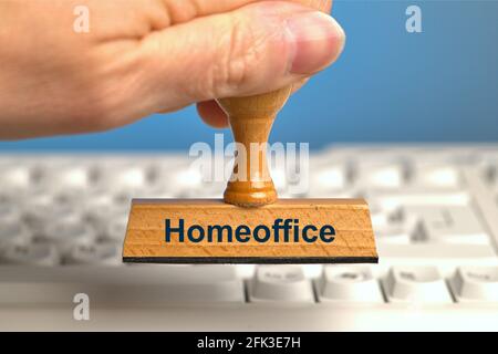 Deutschland. April 2021. Ein Holzstempel mit der Aufschrift „Homeoffice“, der von einer Hand in einem Bluten über einer weißen Computertastatur gehalten wird. Foto mit Komposition vor blauem Hintergrund. Das Home Office ist an der Tagesordnung und wird, wo immer möglich, von Experten empfohlen. Credit: dpa/Alamy Live News Stockfoto