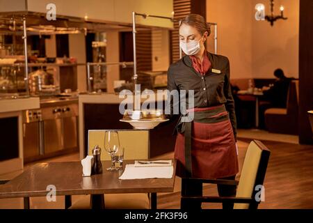 Die Kellnerin legt ein Essen im Restaurant auf einen vorbereiteten Tisch Stockfoto