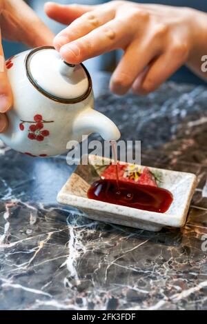 Eine Frau, die japanisches Essen isst, gießt Sojasauce Stockfoto