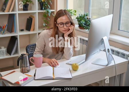 Junge Studentin, die zu Hause am Computer arbeitet Stockfoto
