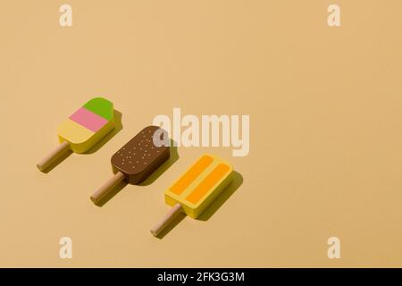 Farbenfrohe, sonnenbeschienenen Eiszapfen auf einem hellgelben Hintergrund. Minimales Eis-Layout. Stockfoto