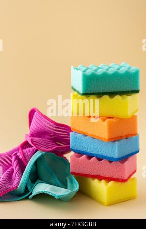 Stapel von bunten Spülschwämmen und Mikrofaser-Servietten auf neutralem beigen Hintergrund, Küchenhaushalt und Reinigungskonzept Stockfoto
