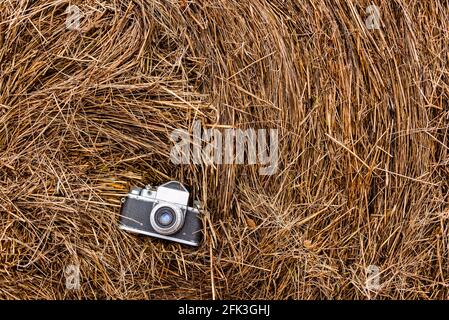 Alte Filmkamera, die auf einem Heustapel liegt, natürlicher Hintergrund. Horizontales Foto von oben Stockfoto