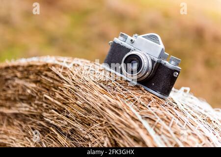 Alte Filmkamera, die auf einem Heuhaufen liegt, natürlicher Hintergrund. Horizontales Nahaufnahme-Foto Stockfoto