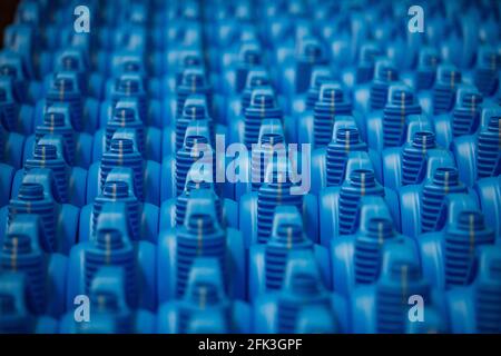 Blaue Motorölbehälter aus Kunststoff an der Förderlinie. Nahaufnahme mit unscharfem Hintergrund. Stockfoto