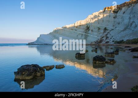 Realmonte, Agrigento, Sizilien, Italien. Blick über die Bucht auf die Scala dei Turchi, Sonnenaufgang, weiße Kalksteinfelsen, die sich im ruhigen Meer spiegeln. Stockfoto