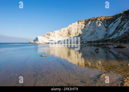Realmonte, Agrigento, Sizilien, Italien. Blick über die Bucht auf die Scala dei Turchi, am frühen Morgen, weiße Kalksteinfelsen, die sich in einem ruhigen Meer spiegeln. Stockfoto