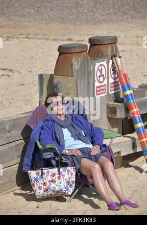 Eine alleinreisende ältere Frau schläft in der Nachmittagssonne am southwold Beach suffolk england Stockfoto