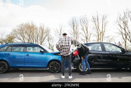 Junge männliche und weibliche Fahrer, die einen beschädigten Autoschlag betrachten Von hinten nach Verkehrsunfall Stockfoto