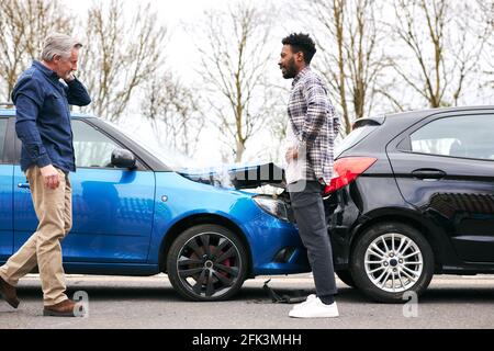 Ältere und jüngere männliche Fahrer steigen aus den Autos und Schäden nach einem Verkehrsunfall untersuchen Stockfoto