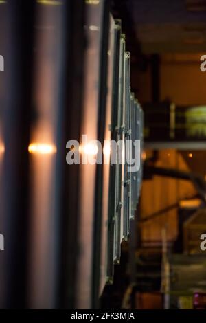 Verarbeitungsanlage für Golderz. Blick auf Reflexionslicht von Metallsieb-Shaker-Körper aus glänzendem Metall. Geringe Schärfentiefe, Werkstattinnenraum verschwommen. Stockfoto