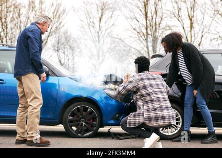Junges Paar machen Fotos auf dem Handy von Schäden an Auto in Unfall mit Senior-Fahrer Stockfoto