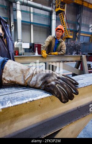 Kasachstan, nur-Sultan. Lokomotivbau. Zwei Arbeiter in der Werkstatt. Konzentrieren Sie sich auf den Wildleder-Schutzhandschuh im Vordergrund. Stockfoto