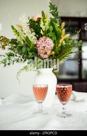 Eleganter Blumenstrauß auf einem Tisch, begleitet von zwei Cocktails Becher in einem geräumigen, modernen Haus Stockfoto