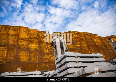 Gelber Wärmedämmschaum an der Wand des Industriegebäudes. Stapel grauer Betonschleifer im Vordergrund. Stockfoto