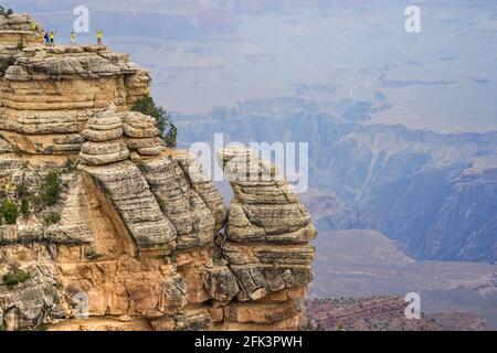 Touristen, die gefährlich nahe am Rand des Grand Canyon wandern, geben einen Eindruck von der Pracht der Landschaft und der Kleinheit des Menschen Stockfoto