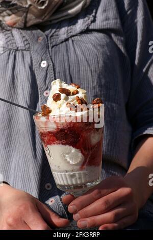 Junge Frau hält köstliche Eisbecher Schale Glas Vanille Erdbeerwalnuss Stockfoto
